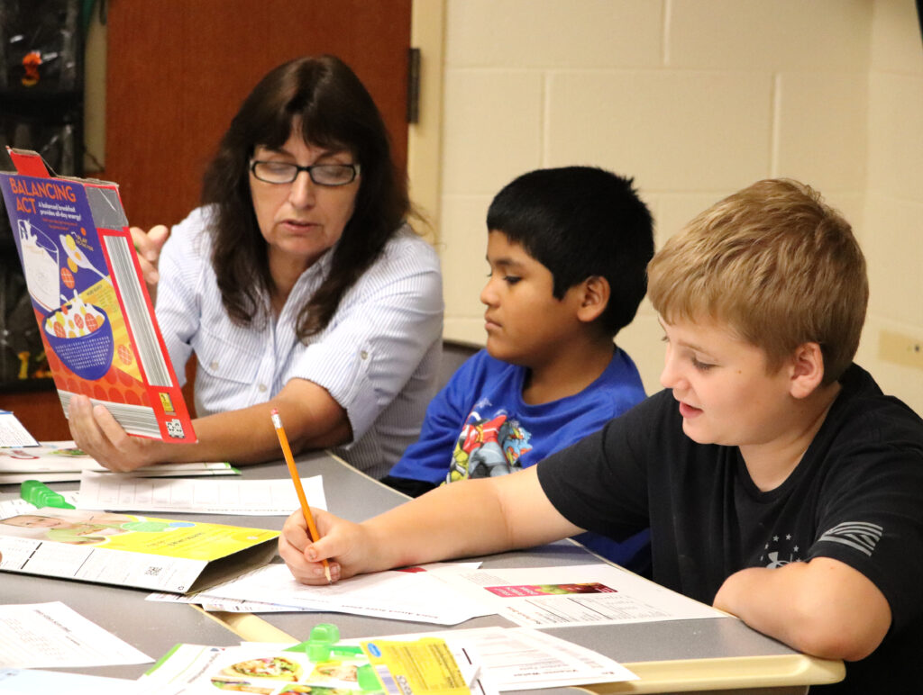 teacher reading instructions on being healthy to two students at a table