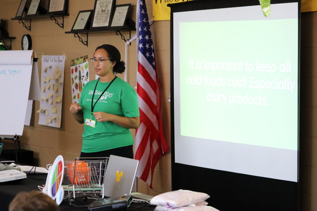 teacher standing by projector screen teaching a class