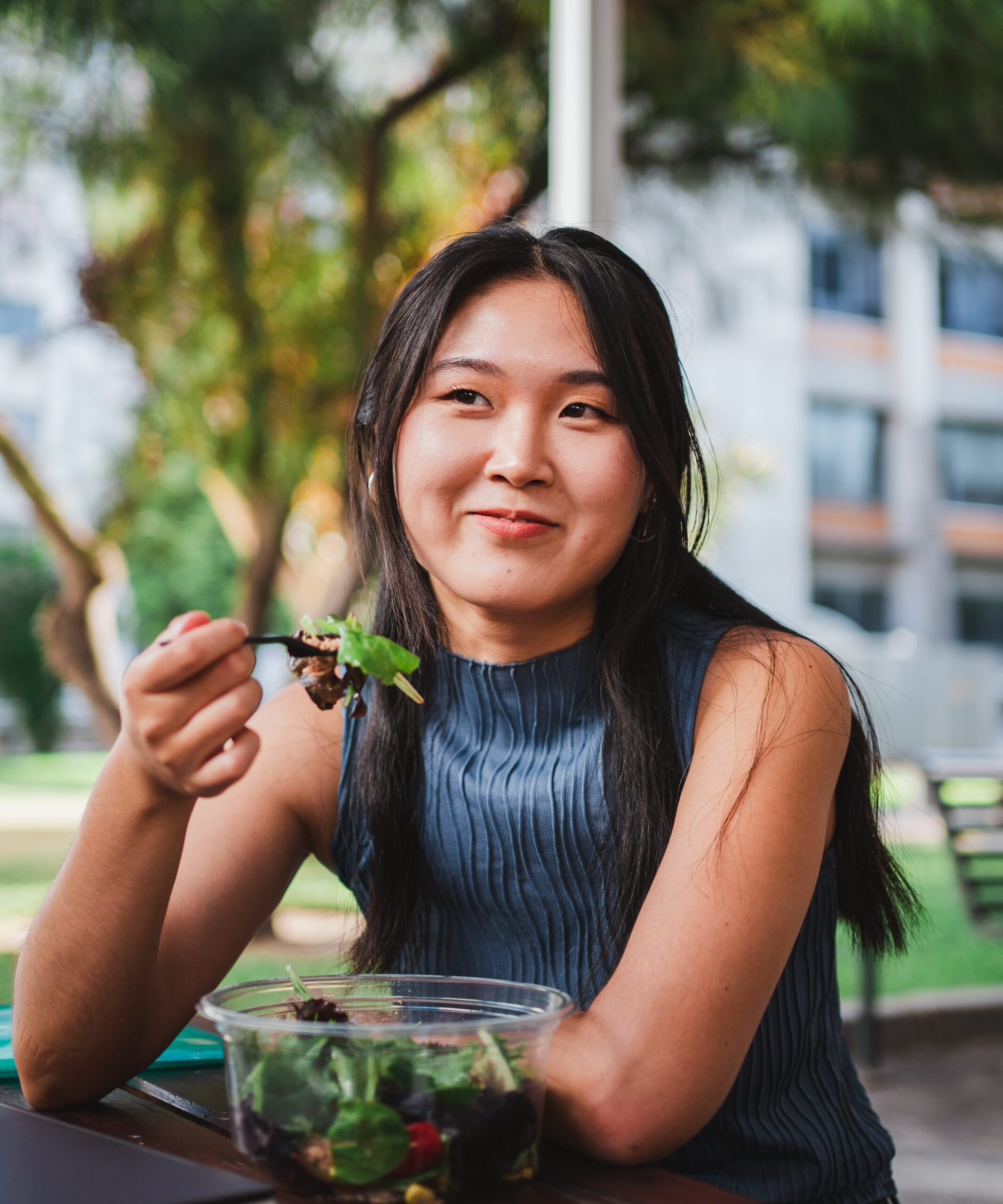 woman eating a salad and holding up her fork at table 