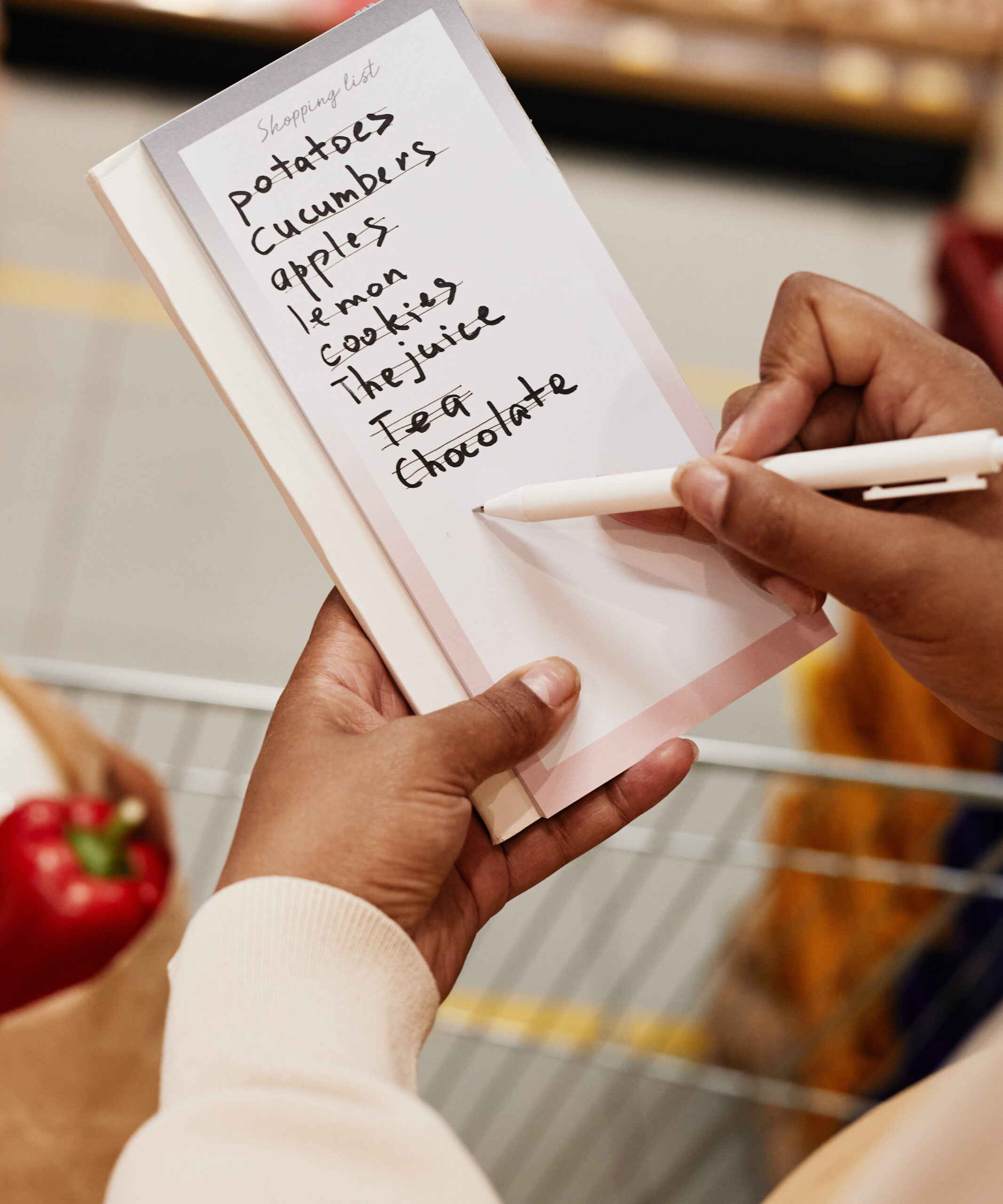 grocery list being held by a set of hands with pen 