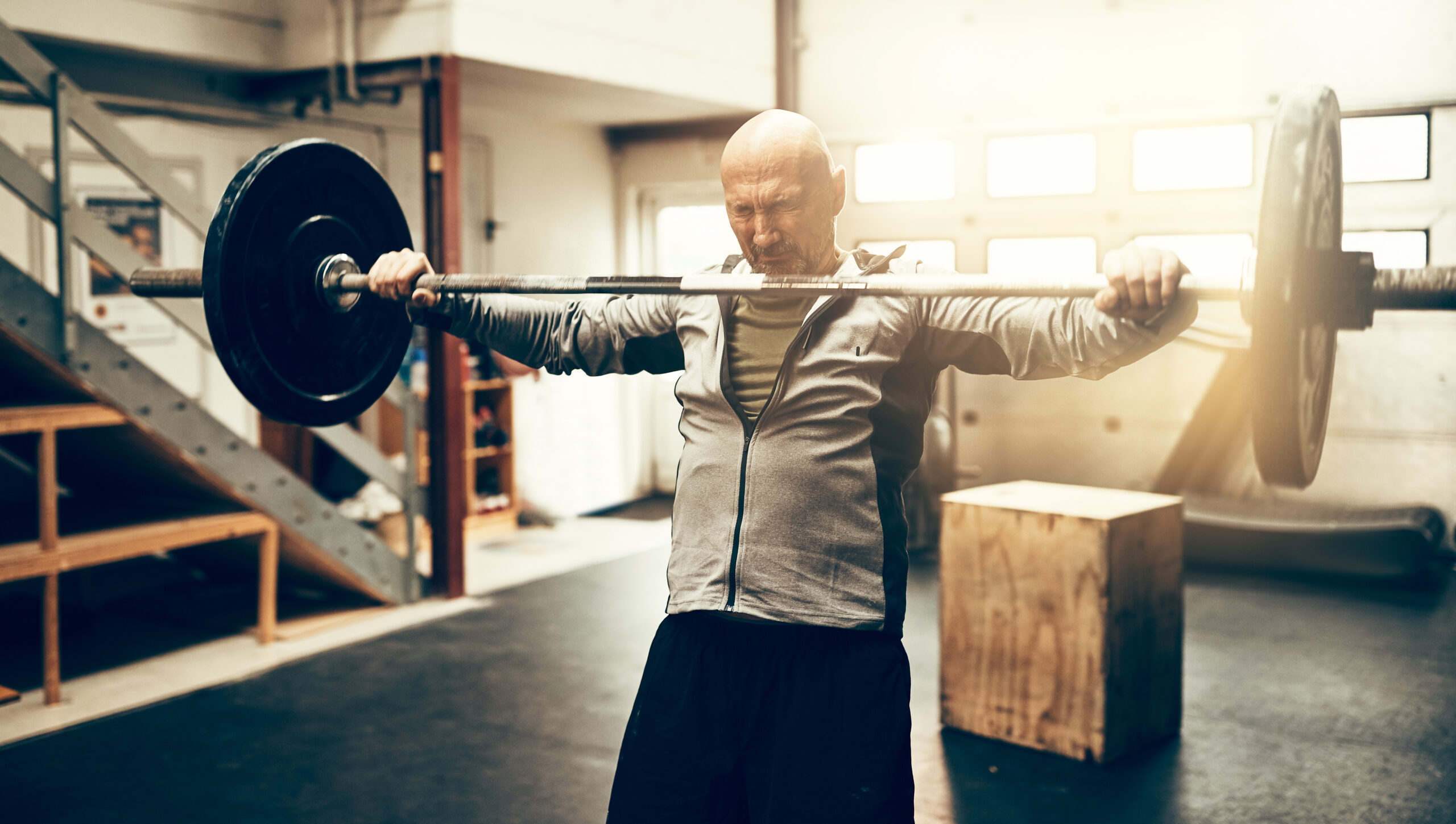 man holding a weighted barbell in gym